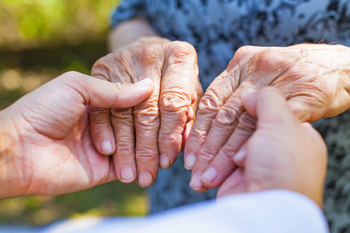 man holding hands of parkinson patient